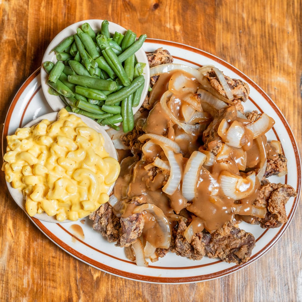 Smothered fried steak with onions and gravy, served with mac and cheese and green beans.