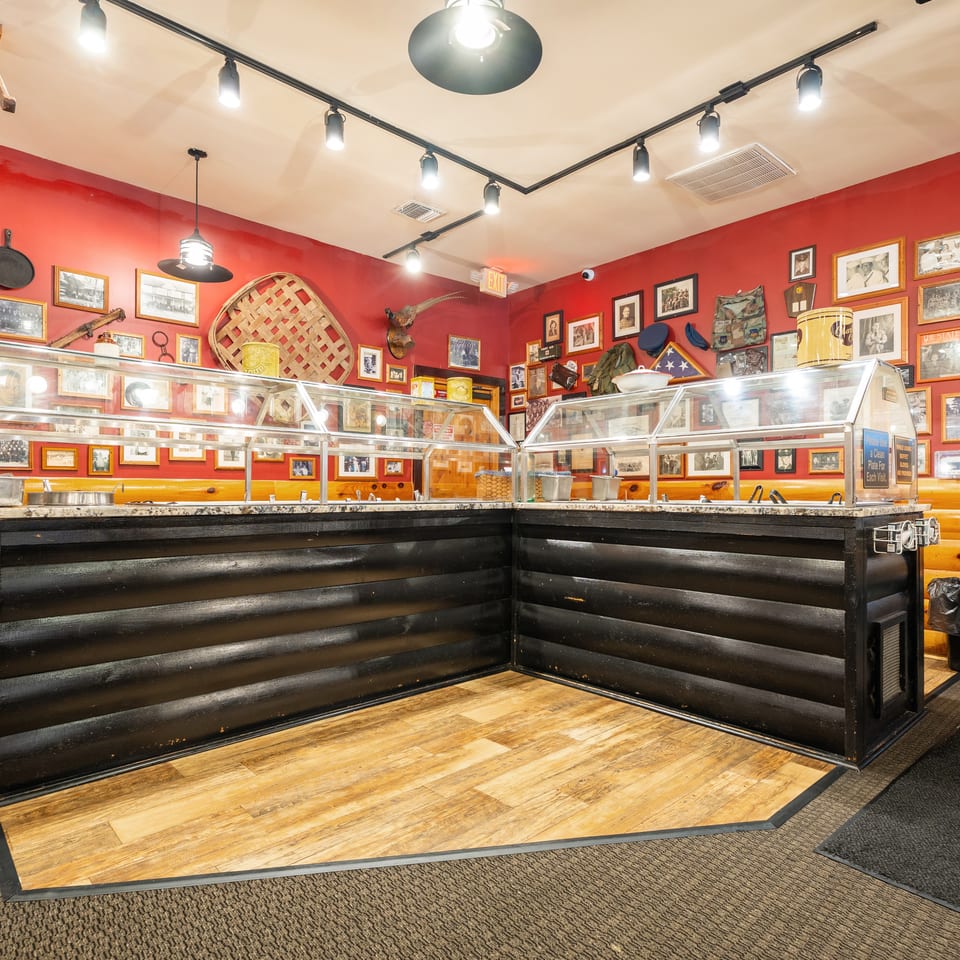 Restaurant buffet counter with dark wood, red walls adorned with many framed pictures, and track lighting.